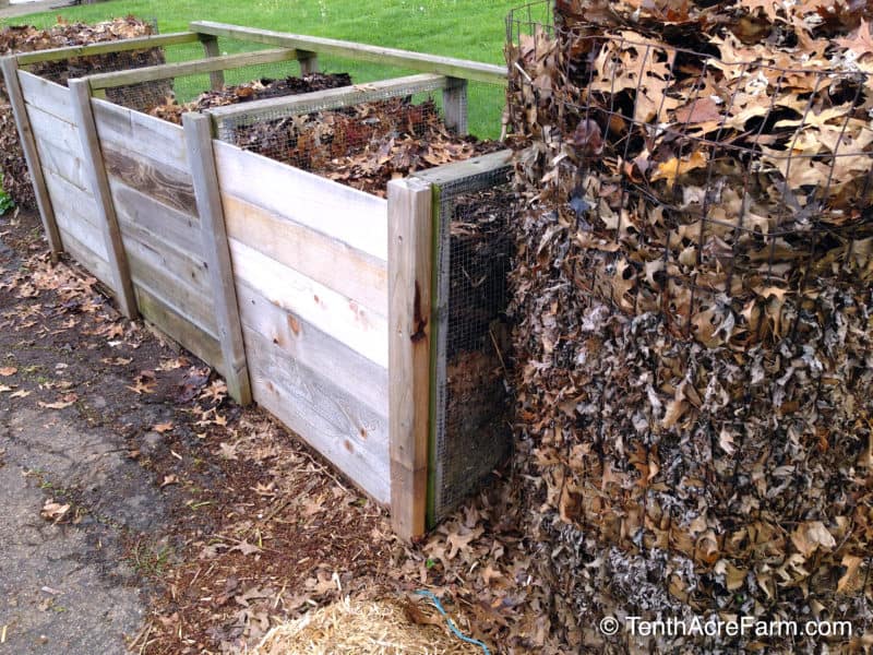 A round wire compost bin sits to the right of a wooden 3-bin unit.